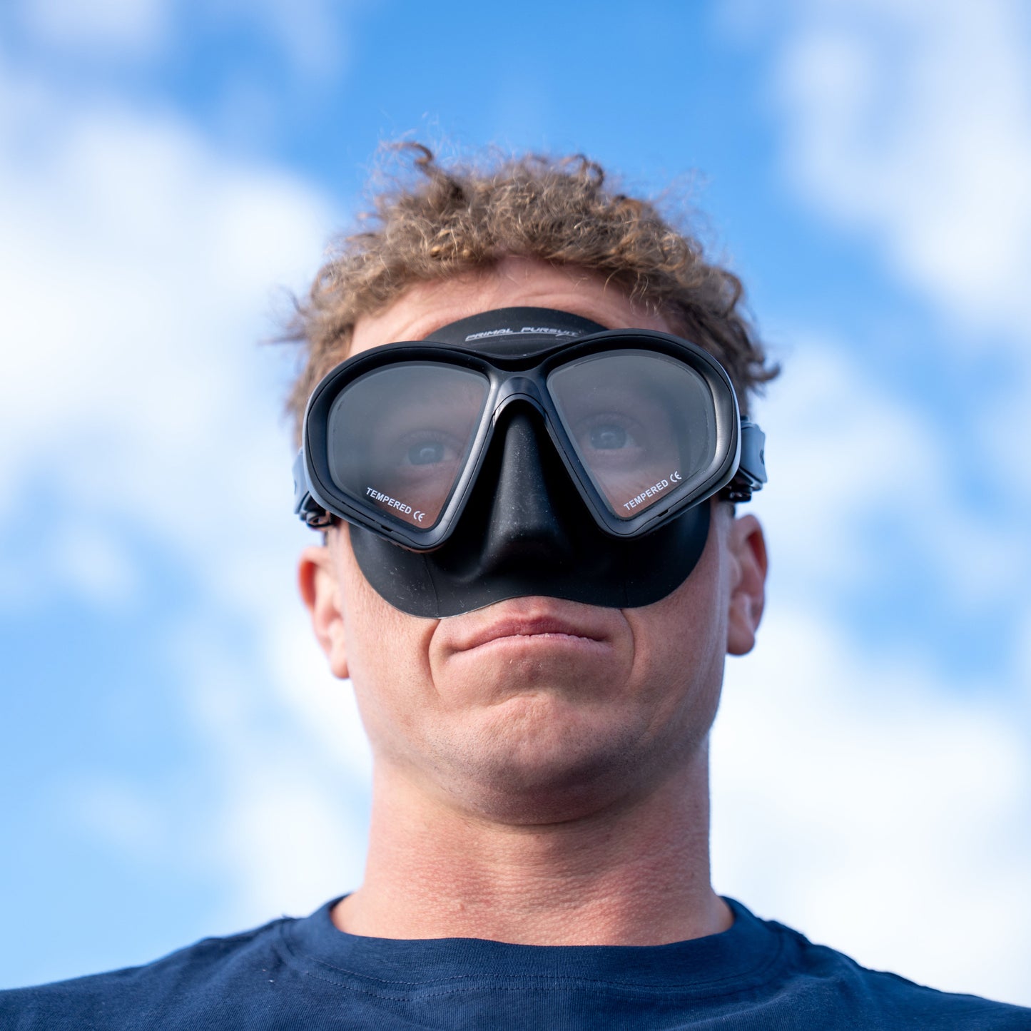 Person wearing a diving mask against a blue sky background