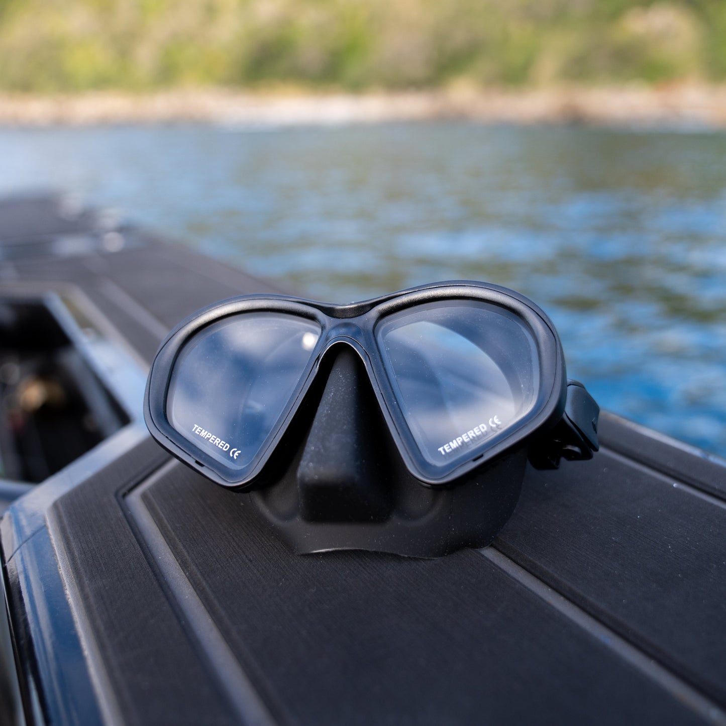 Scuba diving mask on a boat with water and trees in the background