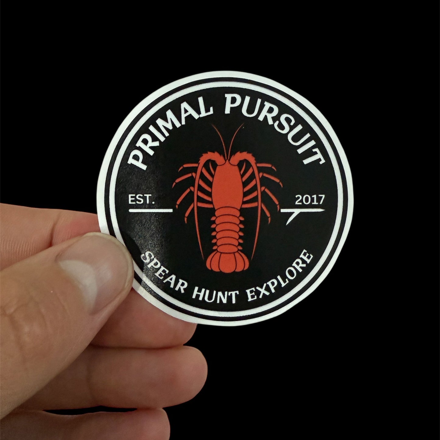 Sticker with 'Primal Pursuit' logo featuring a red lobster on a black background.