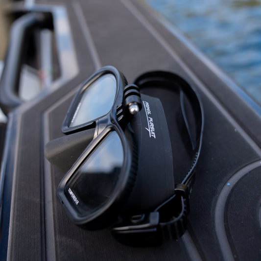 Black diving mask on a boat with water in the background