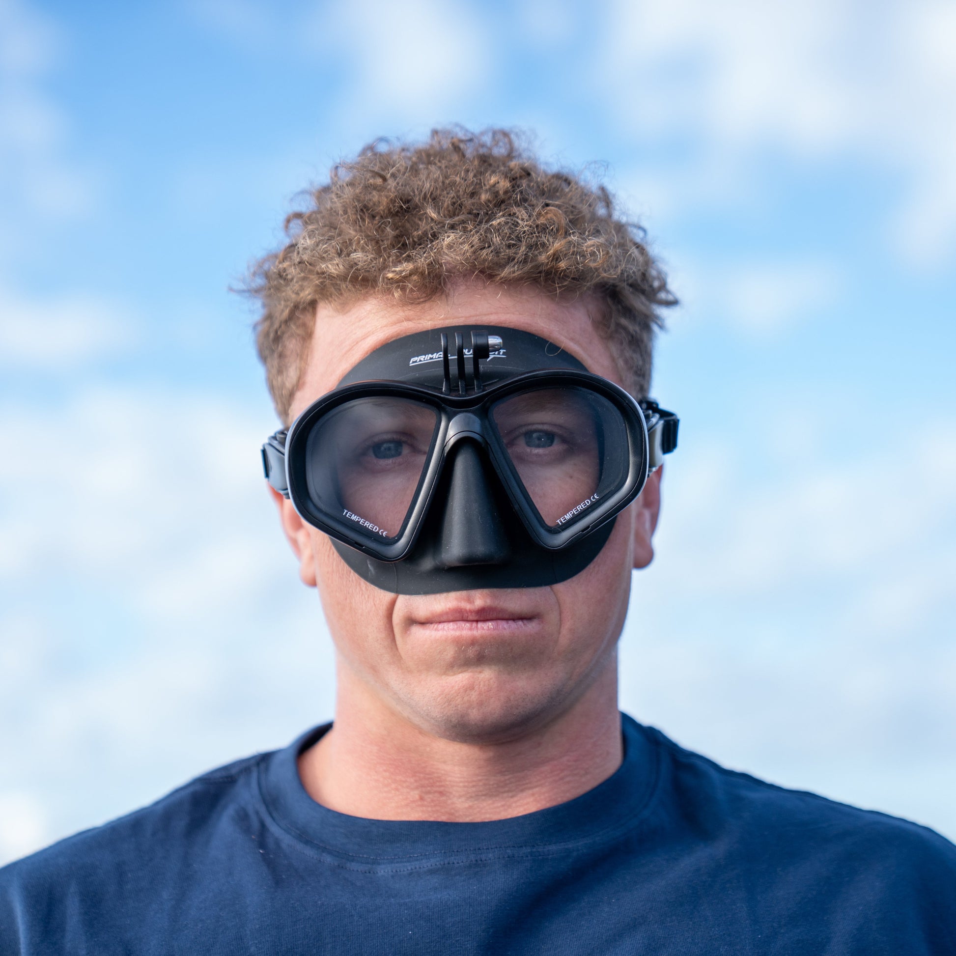 Person wearing a diving mask with a blue sky and water background