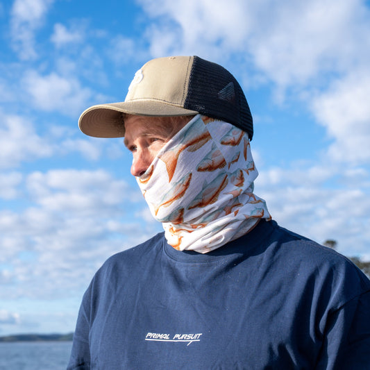 Person wearing a face mask and cap outdoors with a blue sky and water background