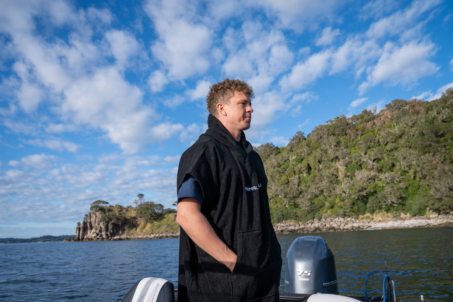 Person standing on a boat with a scenic background of water and hills.