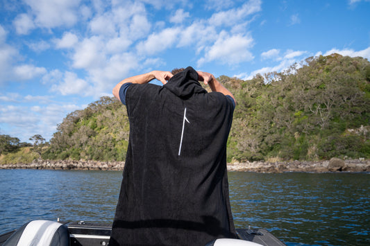Person on a boat looking towards a scenic landscape with trees and blue sky.